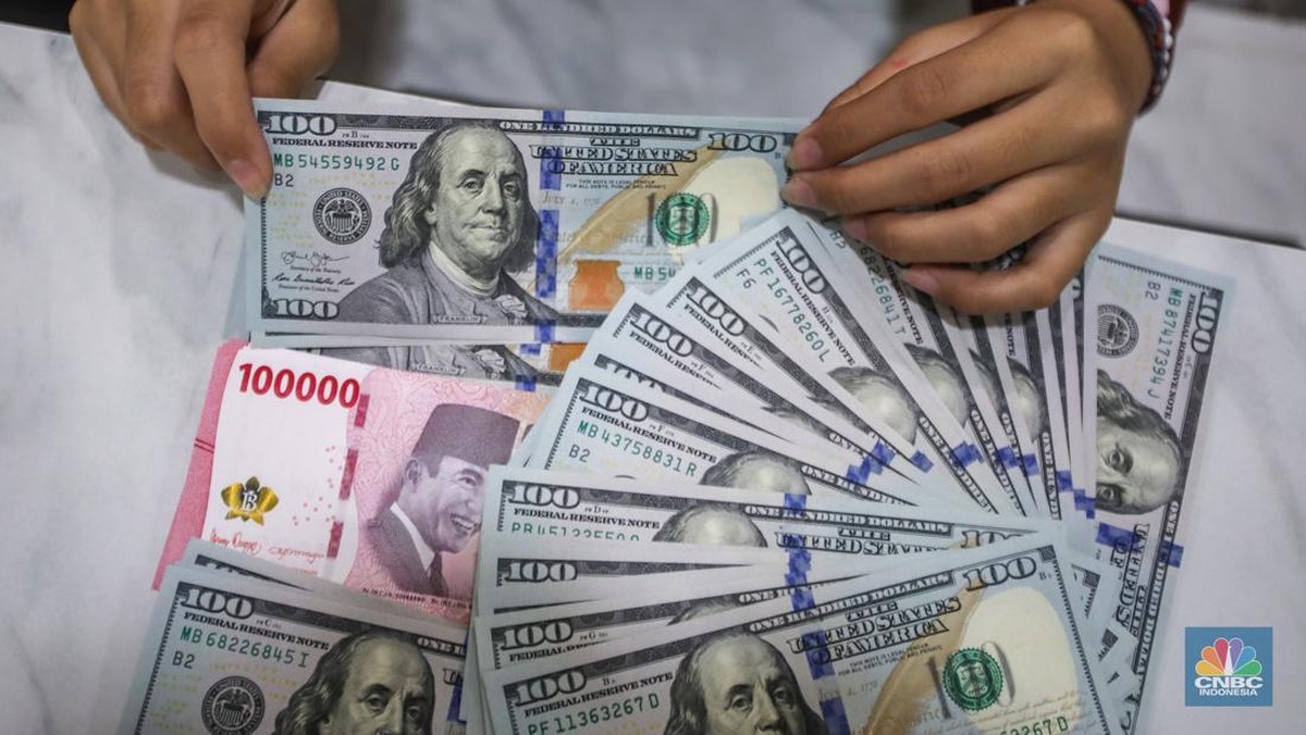 Foto: Petugas menjunjukkan uang pecahan dolar AS dan rupiah di Dolarindo Money Changer, Jakarta, Selasa (8/4/2025). (CNBC Indonesia/Faisal Rahman)
