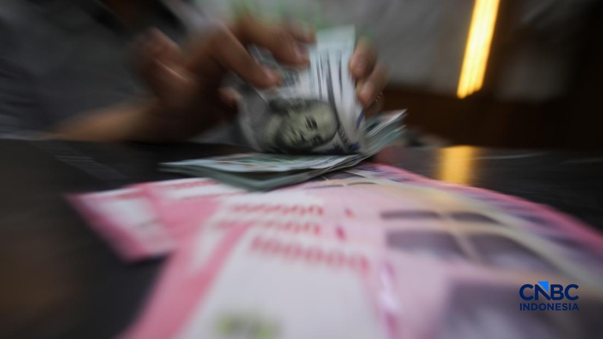 Petugas menjunjukkan uang pecahan dolar Amerika Serikat (AS) dan rupiah di Dolar Asia Money Changer, Jakarta, Rabu (8/7/2026). (CNBC Indonesia/Faisal Rahman)